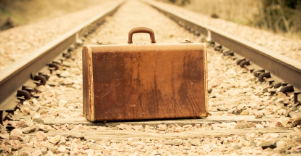 Old suitcase sitting on rail road tracks